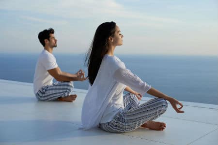 A young couple are meditating near the ocean