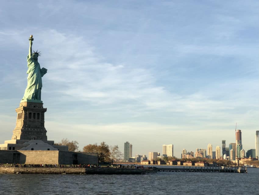 A picture of the statue of liberty with Manhattan in the background.